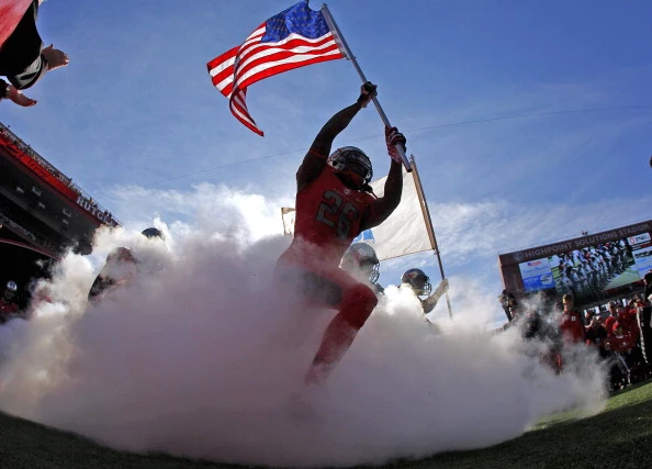 Johnathan Aiken #26 of the Rutgers Scarlet Knights carries the American flag out as he leads his team onto the field before the start of their game against the Cincinnati Bearcats Johnathan Aiken #26 of the Rutgers Scarlet Knights carries the American flag out as he leads his team onto the field before the start of their game against the Cincinnati Bearcats